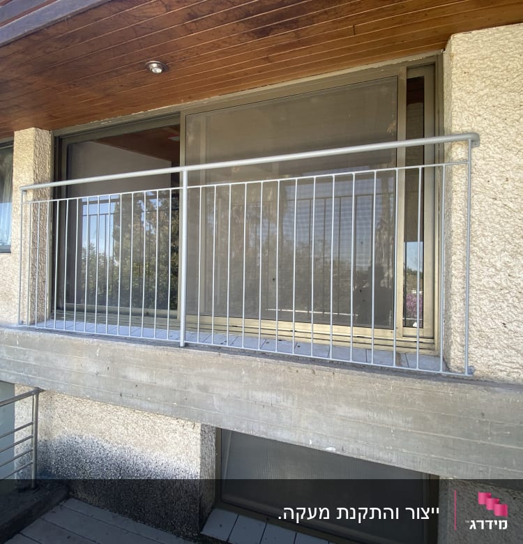 מעקה מתכת אפור על מרפסת בטון